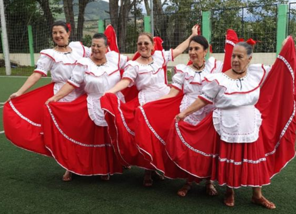 Imagen de mujeres con vestidos típicos de rojo y blanco posando para foto