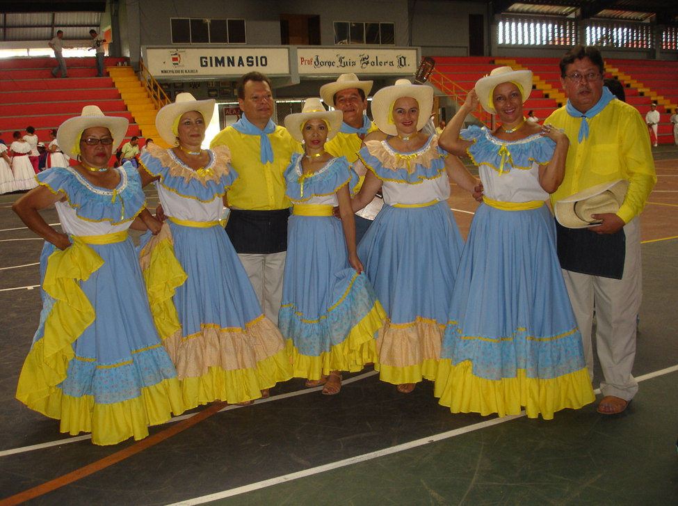 Imagen de grupo posando con trajes típicos celes y amarillo en gimnasio